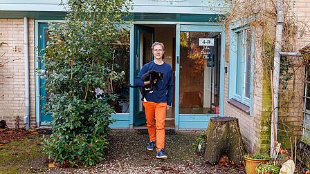 John van Duursen voor zijn woning met een kat in zijn handen