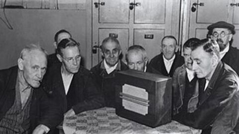 Foto van personen die naar de radio luisteren tijdens de Tweede Wereldoorlog