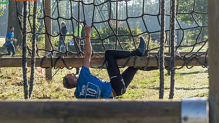 Een man hangt aan een balk tijdens de Tuxis Ede's Best Run