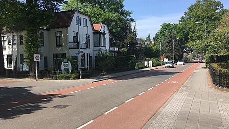 Stationsweg bij een kruising met tegemoetkomende auto en fietser in de verte