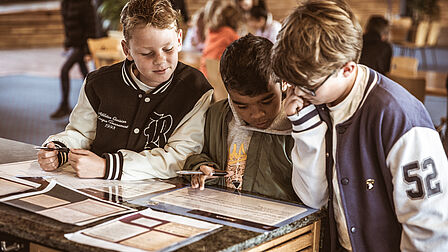 Drie jongens lezen een informatiebord. 