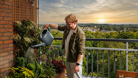 Afbeelding van Herman die planten water geeft op zijn balkon