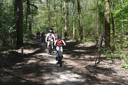Kinderen en ouders rijden in het bos op een mountainbike